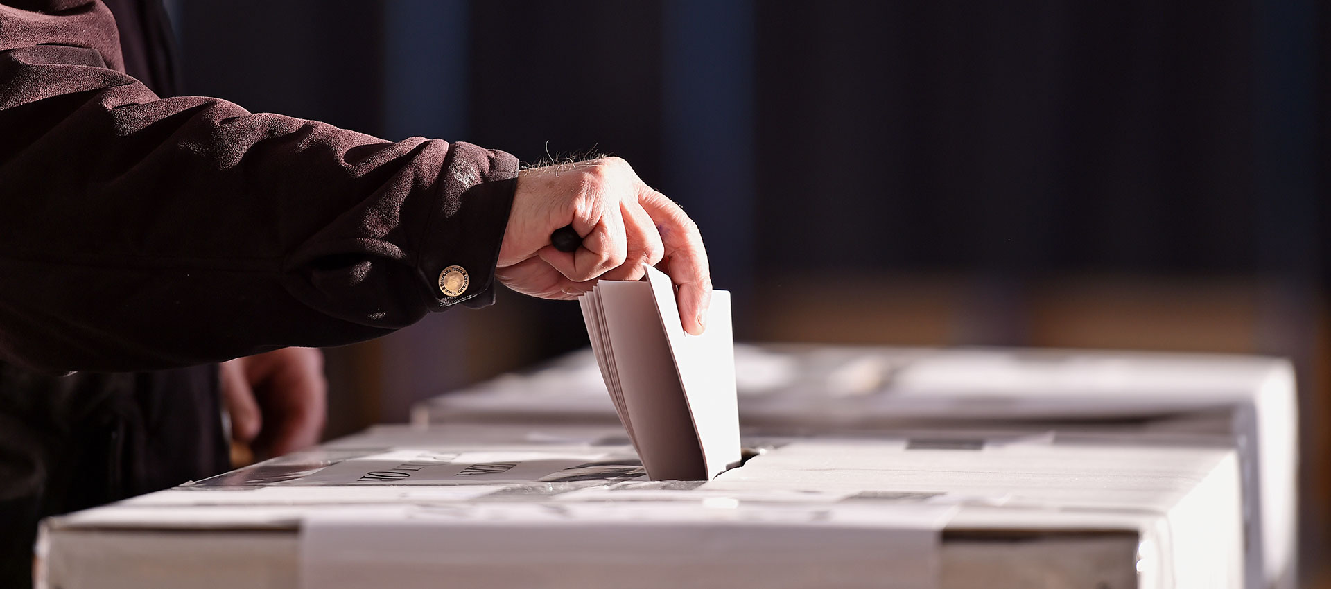 Close up of a mans hand putting a piece of paper in to a drop box.