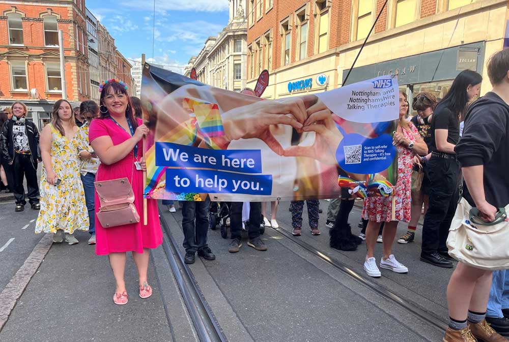 A woman in a pink dress holds a banner reading 