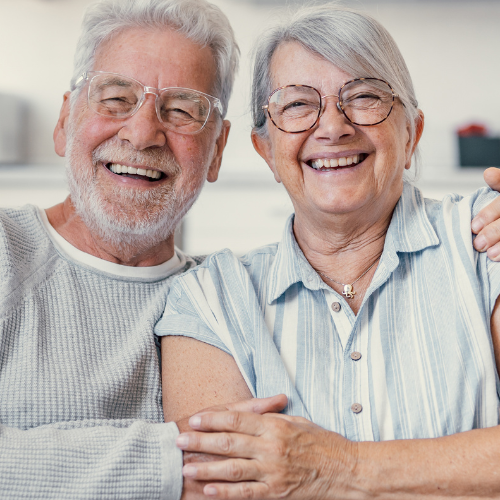 Two people sitting close together with their arms around each other, showing a warm and supportive connection in a home setting.